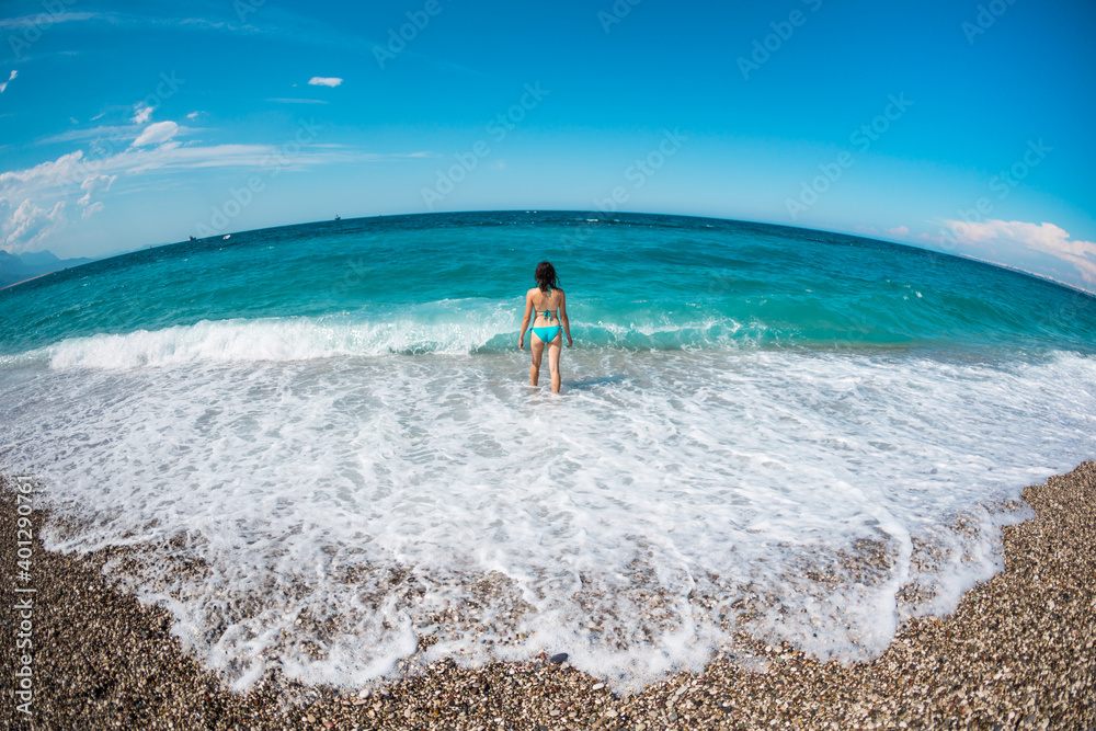 A girl in a swimsuit walks along the beach