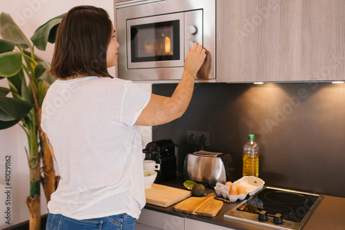 Woman using a microwave for preparing poached eggs