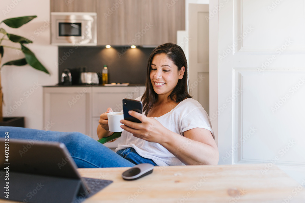 Smiley brunette girl using a smartphone in the modern kitchen Smiley brunette girl using a smartphone in the modern kitchen
