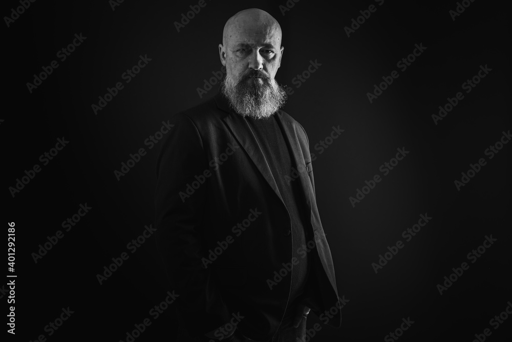 Obraz premium close up photo, portrait of a serious, thoughtful, bearded man on a dark background confident and dramatic looking straight. Concept of male portrait. Black and white photo. Low key