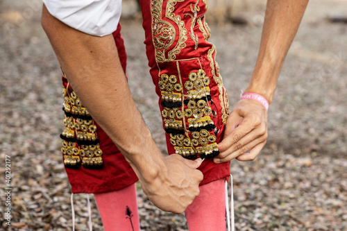 Crop unrecognizable young male bullfighter putting on traditional shiny red costume while preparing for performance