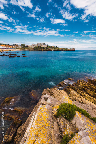 From above spectacular view of rippled ocean near rough mounts and residential buildings under sky in Spain
