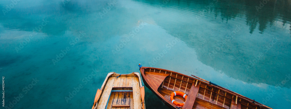 From above wooden boat with paddles floating on turquoise water of calm lake on background of majestic landscape of highlands