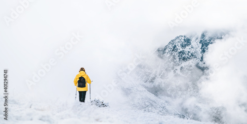 Back view of anonymous hiker with trekking poles walking on snowy ground in Pyrenees mountains in Andorra