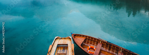 From above wooden boat with paddles floating on turquoise water of calm lake on background of majestic landscape of highlands photo