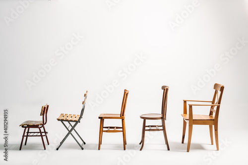 Profile of five old wooden chairs against white background photo