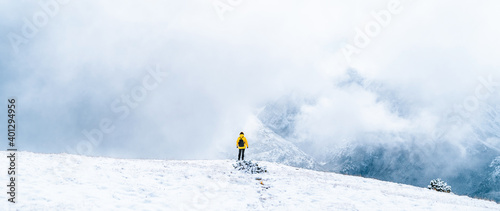 Back view of anonymous hiker with trekking poles walking on snowy ground in Pyrenees mountains in Andorra