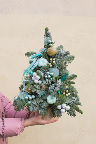 Christmas decorations for home comfort. Gift box with fir, christmas tree branches and New Year's toys in a turquoise hat box. Girl in mittens holds gift for New Year ivent. Background photo