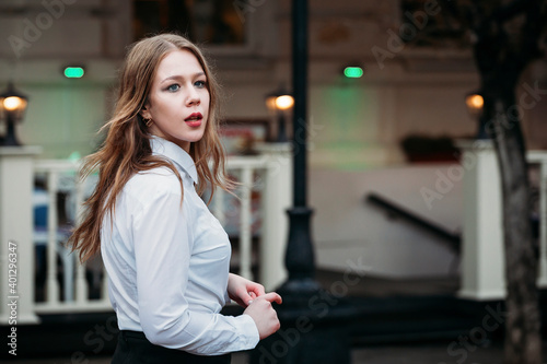 young beautiful blonde businesswoman in office clothes walks through the city after rain