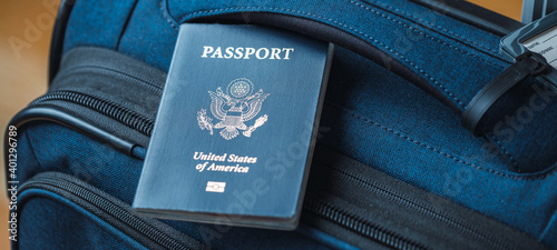 A blue American passport sitting on top of a blue suitcase
