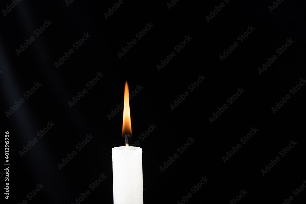Burning candle in front of a black velvet background. There is some drapery on the left. Copy space. Burning candle in front of a black velvet background. There is some drapery on the left. Copy space.