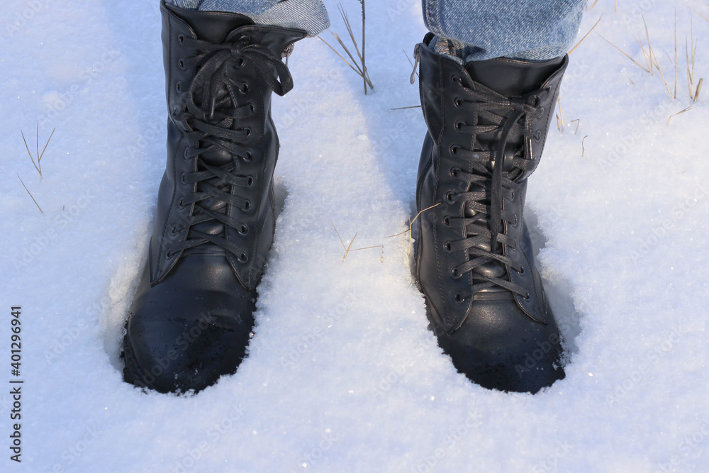 Black boots with laces stand in the snow. Black boots with laces stand in the snow.