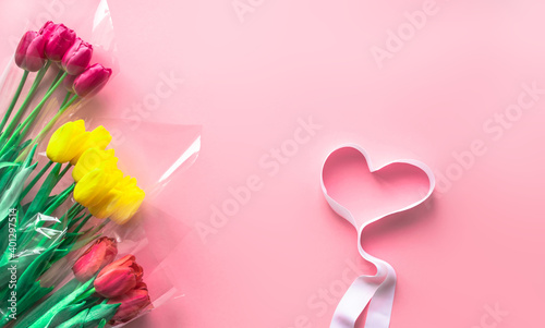 Fresh bouquets of tulips flowers on delicate pastel light pink paper background. Greeting card for Valentine's Day, Mother's or Woman's Day.