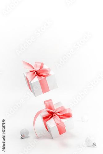 Christmas gift. White gift box with red ribbon, New Year balls in xmas composition on white background for greeting card. Winter festive composition with copy space.