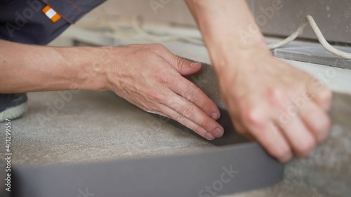 Worker glues damper tape before laying the floor. Reinforcing tape for drywall. Damper tape for screed