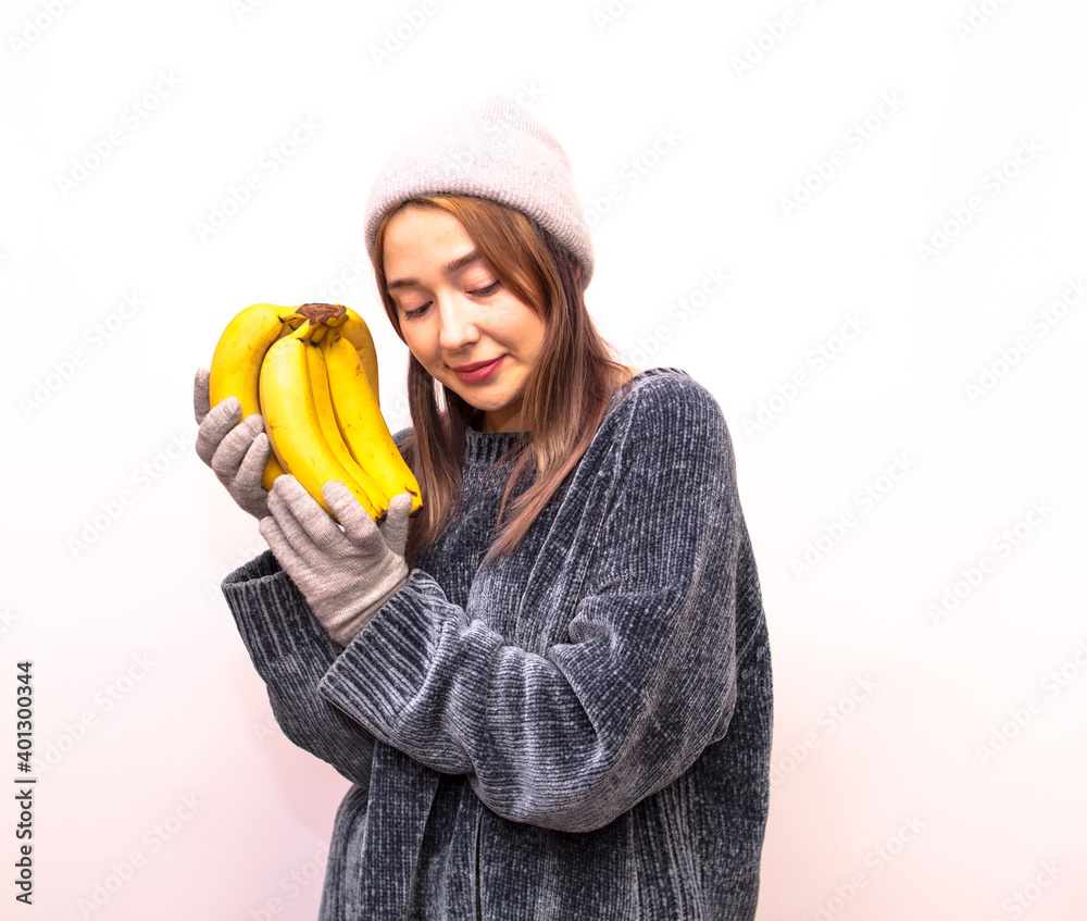 Girl in gray clothes holding bananas isolated on a white background Girl in gray clothes holding bananas isolated on a white background