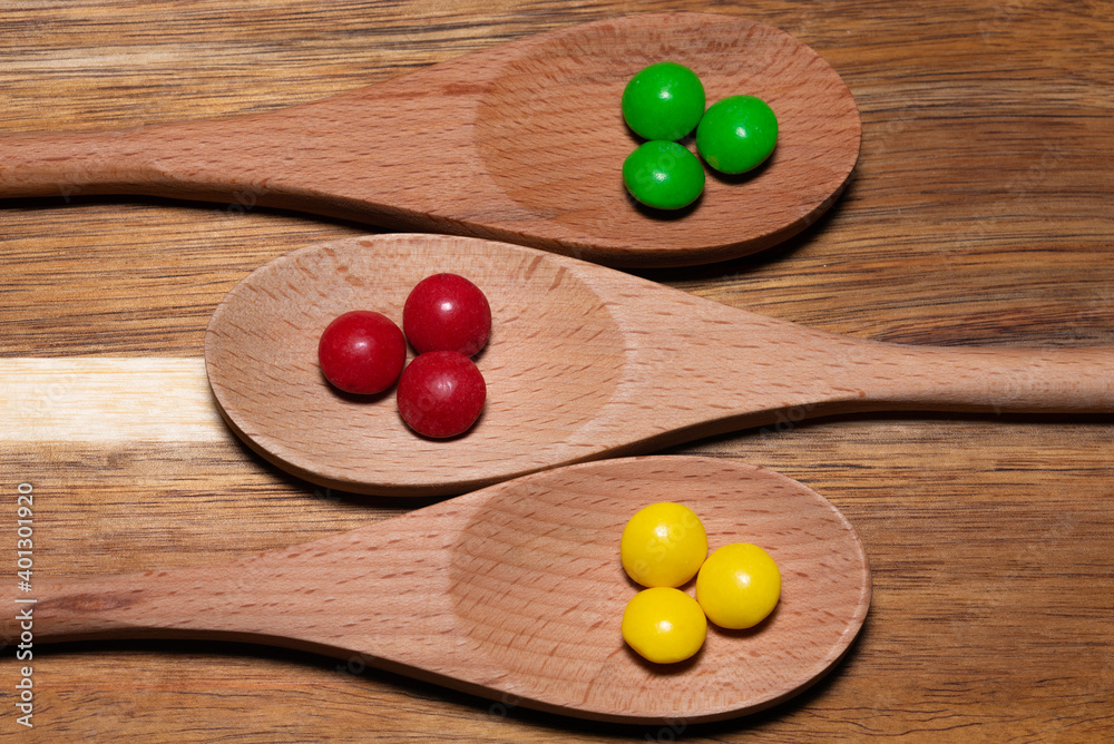Three wood spoons with colorful candies Three wood spoons with colorful candies