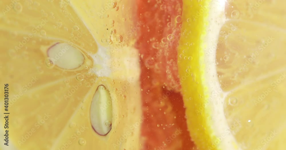Air bubbles move along a slices of lemon in a glass of lemonade, citrus background
