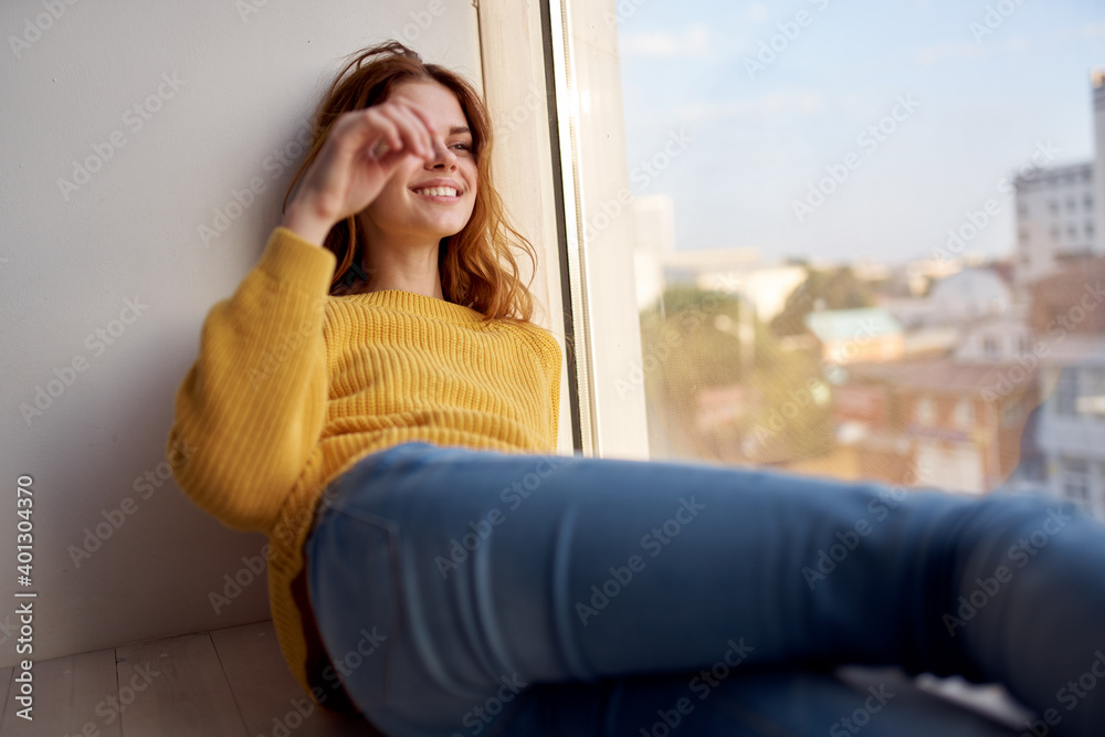 a pretty woman in a yellow sweater lies on the windowsill and looks out the window a pretty woman in a yellow sweater lies on the windowsill and looks out the window