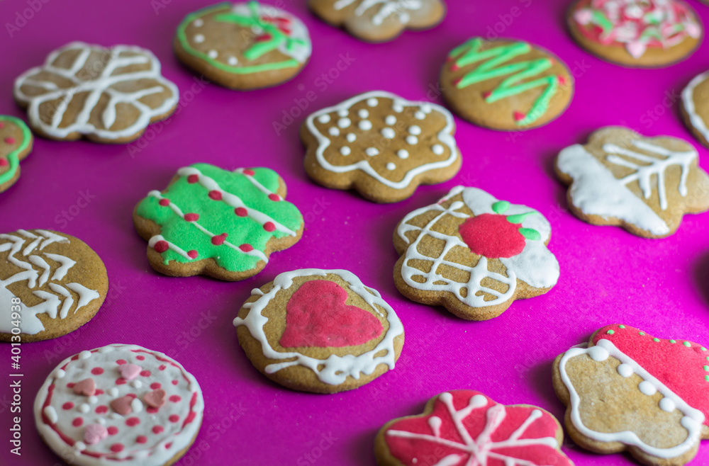 Christmas gingerbread cookies beautifully decorated and assorted on a pink background. 