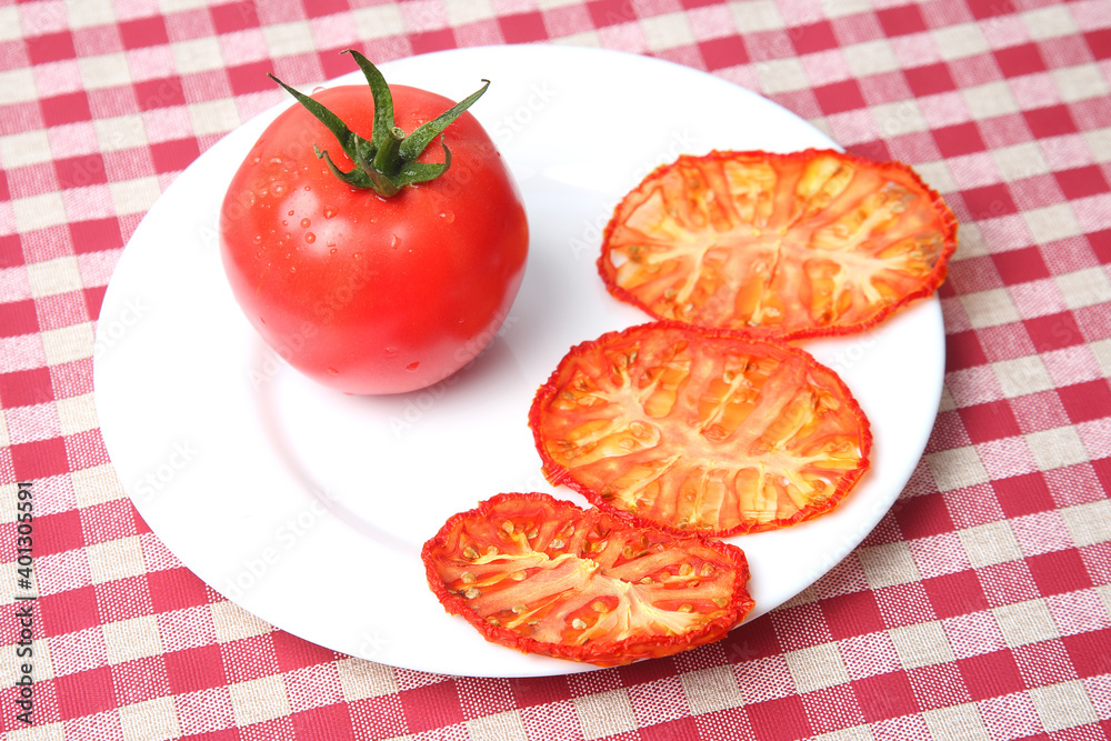 Fresh red tomato and dried tomato slices on a plate. Vitamin vegetable food Fresh red tomato and dried tomato slices on a plate. Vitamin vegetable food