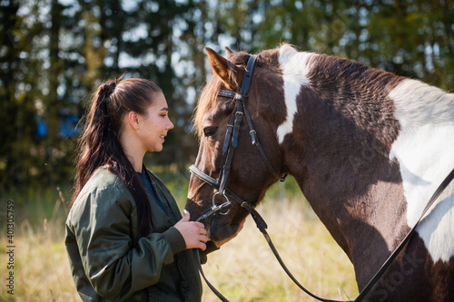 Cute girl talking with her horse after a joint walk in the background of the forest. © Anna Kosolapova