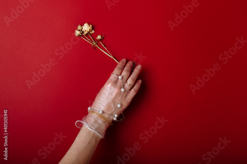 Fashion art hand woman in the glove with Jewelry in summer time and flowers behind her hand with bright contrasting makeup. Creative beauty photo hand skincare