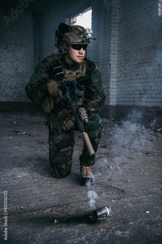 Military man during combat and smoke grenade on a ground.