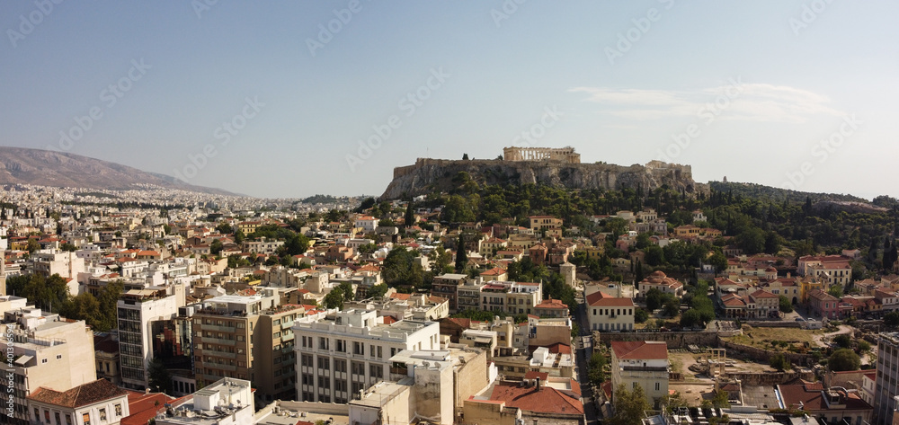Aerial drone shot of beautiful Acropolis monument on hill of Athens during hot summer day.