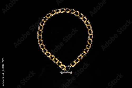 Golden jewelry chain with medallion isolated on black background