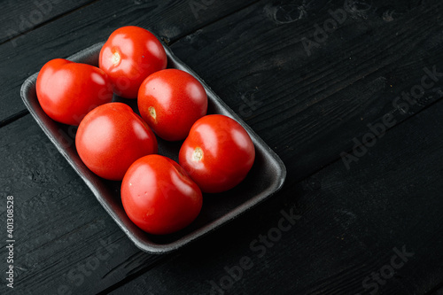 Red tomatoe, on black wooden table with copy space for text