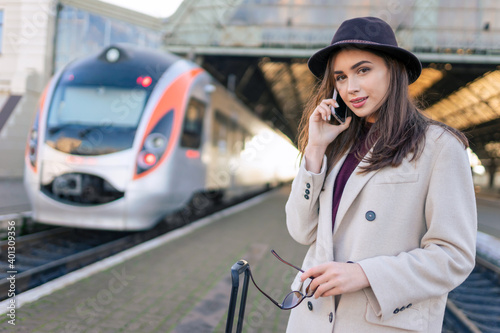 Portrait of young beautiful woman at the railway station who talking on the phone