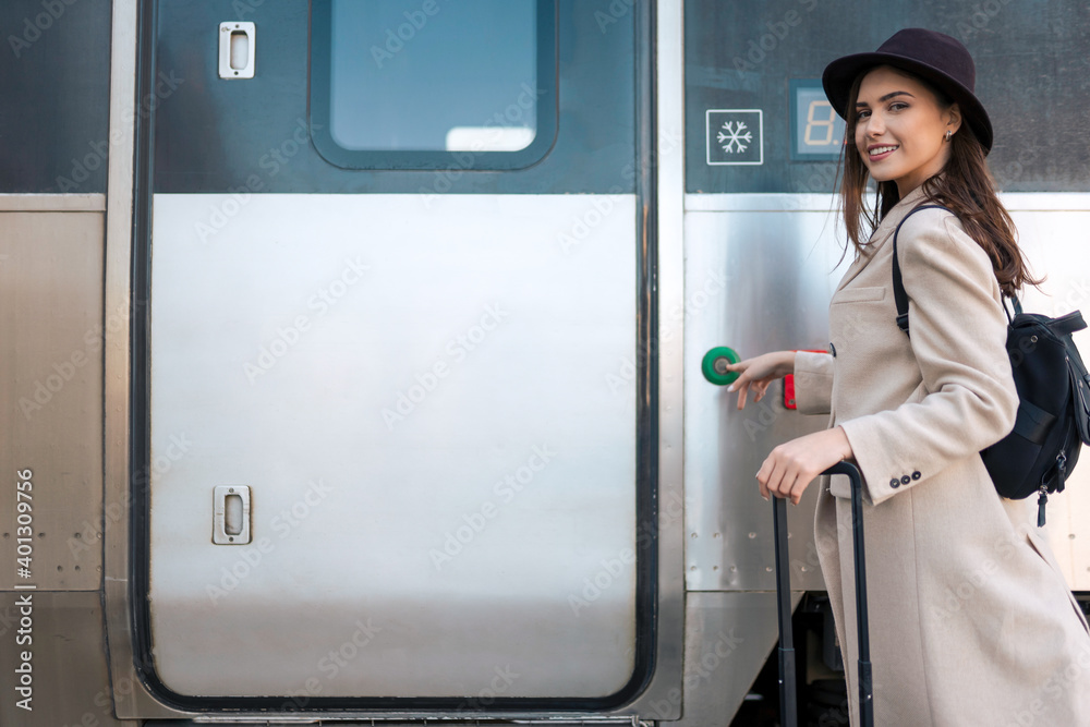 Cheerful woman presses a button on the train door to enter. Female tourist missed the train. Railway trip concept Cheerful woman presses a button on the train door to enter. Female tourist missed the train. Railway trip concept