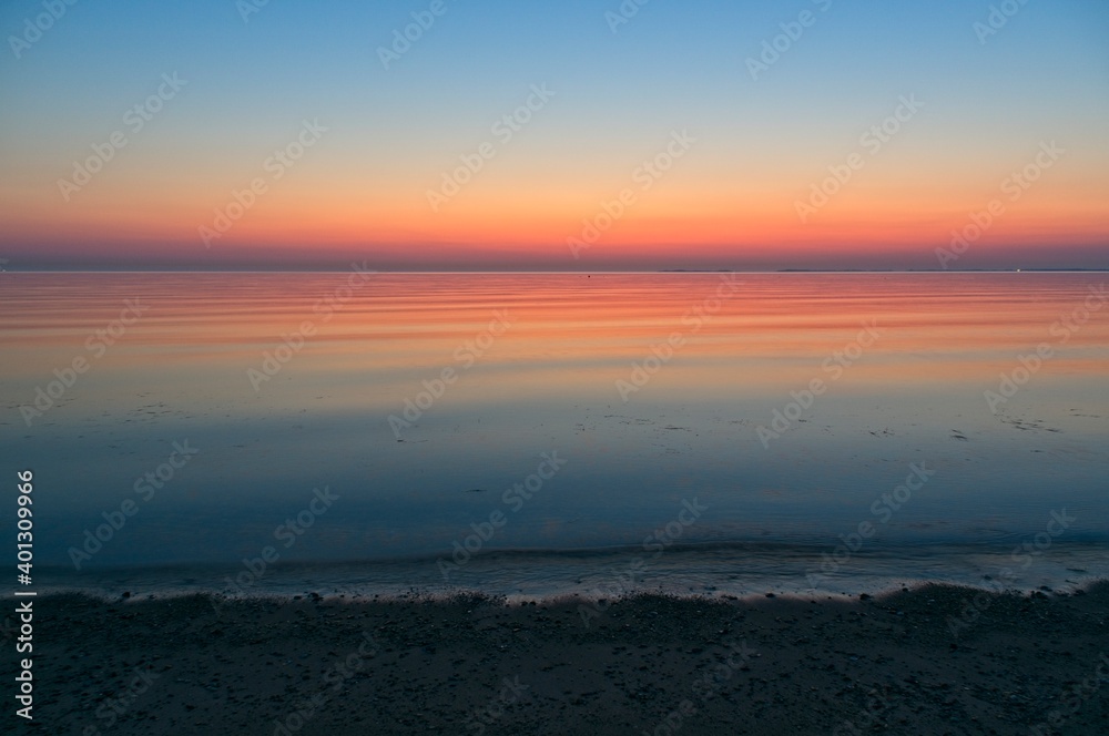 Sunrise at the beach with sand and small rocks.