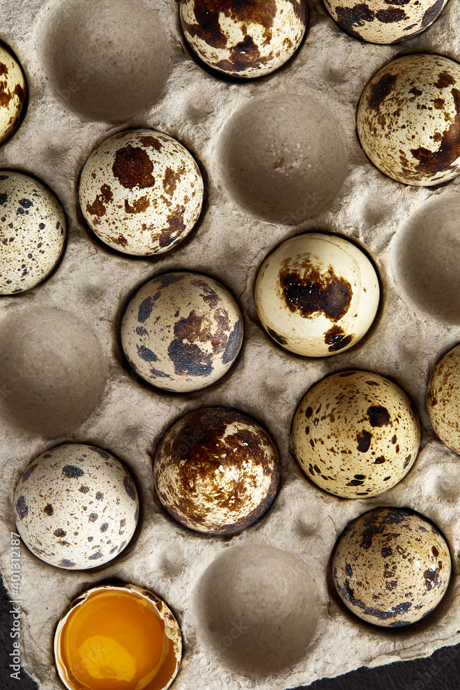 Quail eggs in the cardboard packing on the grey scratched table.