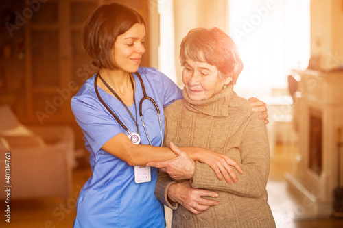 A young nurse shows care and professionalism in relation to an elderly woman, a pensioner. Young woman doctor visits the patient at home and conducts medical therapy
