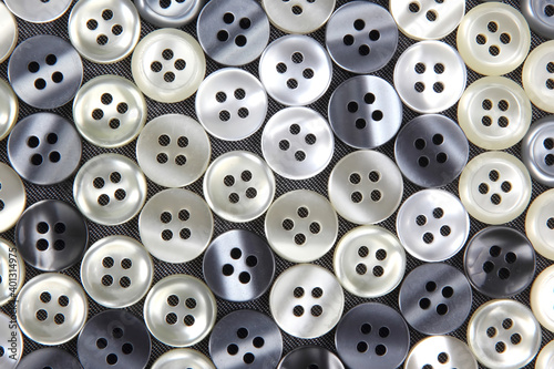 Plastic shiny buttons for clothes on a fabric background. Fashion and clothing. Factory industry