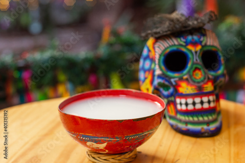 Authentic mexican pulque drink on a table with a colorful huichol skull