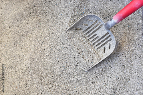 A top view image of fresh cat litter and a red handled pooper scooper.   photo