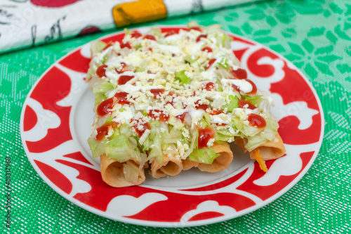 Tacos fritos mexicanos de pollo con crema y queso acompañados de jugo de naranja