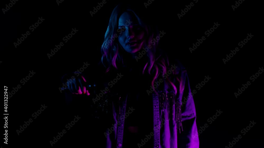 Live vocal performance of emotional singer in darkness on black background. Vocalist girl in pink green neon light dancing, singing performing on concert musician stage. Party, music festival concert Live vocal performance of emotional singer in darkness on black background. Vocalist girl in pink green neon light dancing, singing performing on concert musician stage. Party, music festival concert