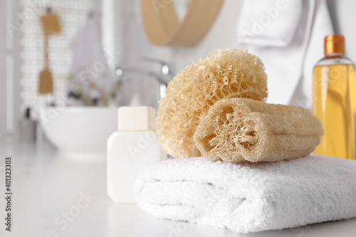 Natural loofah sponges and towel on table in bathroom. Space for text photo