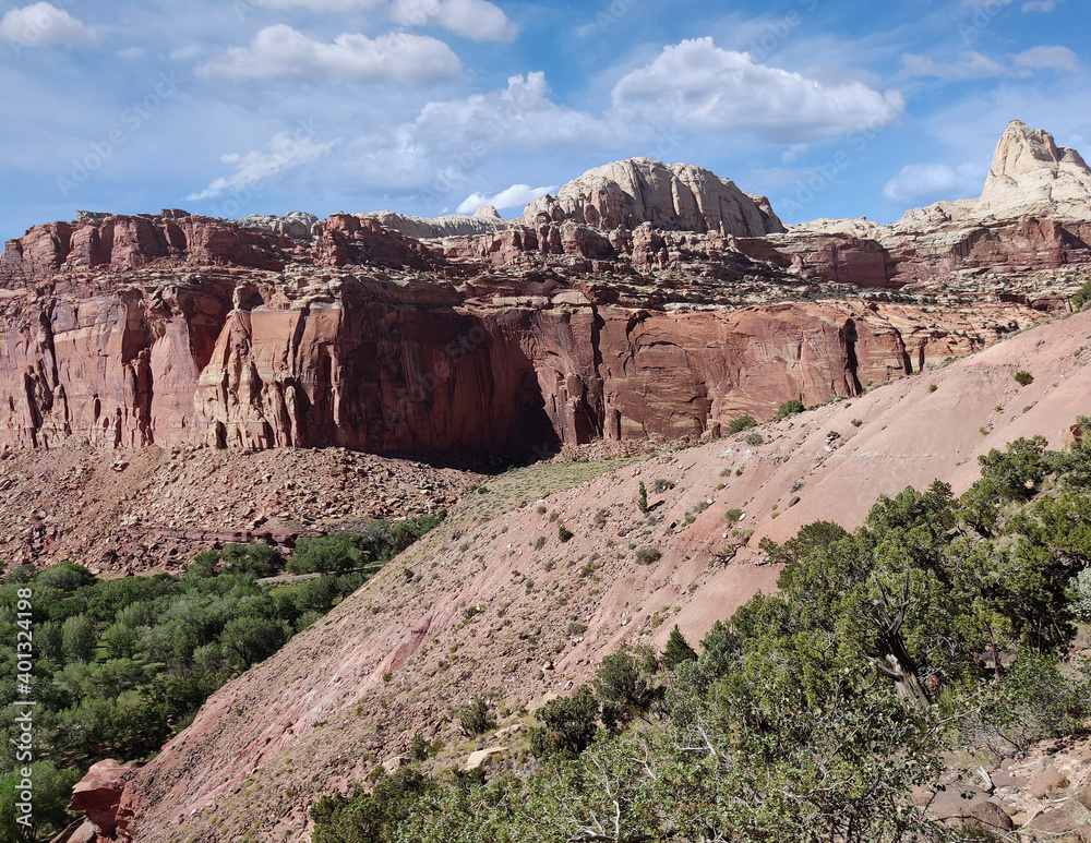 Fototapeta premium Golden sandstone geographical formations with a desert prairie landscape on a hot summer day at the Cohan Canyon Trail in Capitol Reef National Park Southern Utah.