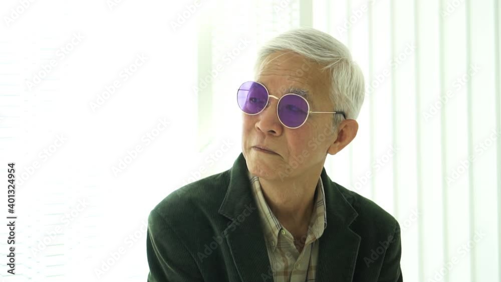 Fashion designer Asian senior model man looking at camera slow motion suit and colorful glasses Fashion designer Asian senior model man looking at camera slow motion suit and colorful glasses