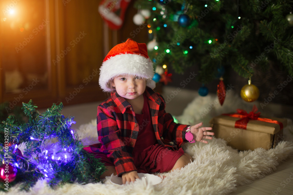 a child in red clothes is sitting waiting for the new year. the concept of celebrating Christmas at midnight. holiday costume