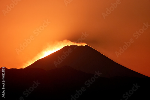 The peak of mountain Fuji with golden clouds and warm sunset light  summer time  Kofu  Yamanashi  Japan. The mountain range in front shows the how big of Mt. Fuji is.