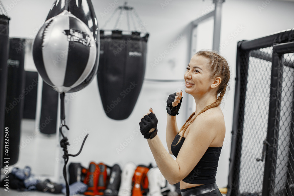Woman boxing. Beginner in a gym. Lady in a black sportwear.