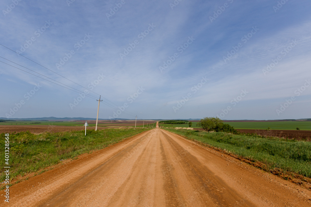 Russian agricultural field. A scenic dirt road passes by agricultural sown fields in Russia.