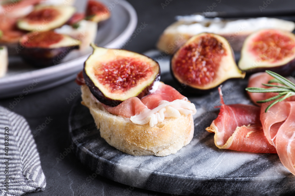 Sandwich with ripe fig, cream cheese and prosciutto served on black table, closeup