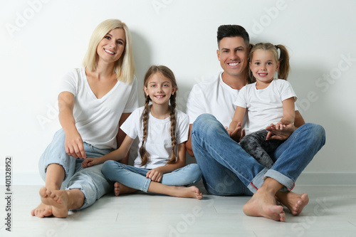 Happy family sitting on floor near white wall